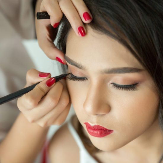 Make-up artist applying liquid eyeliner with brush, close up